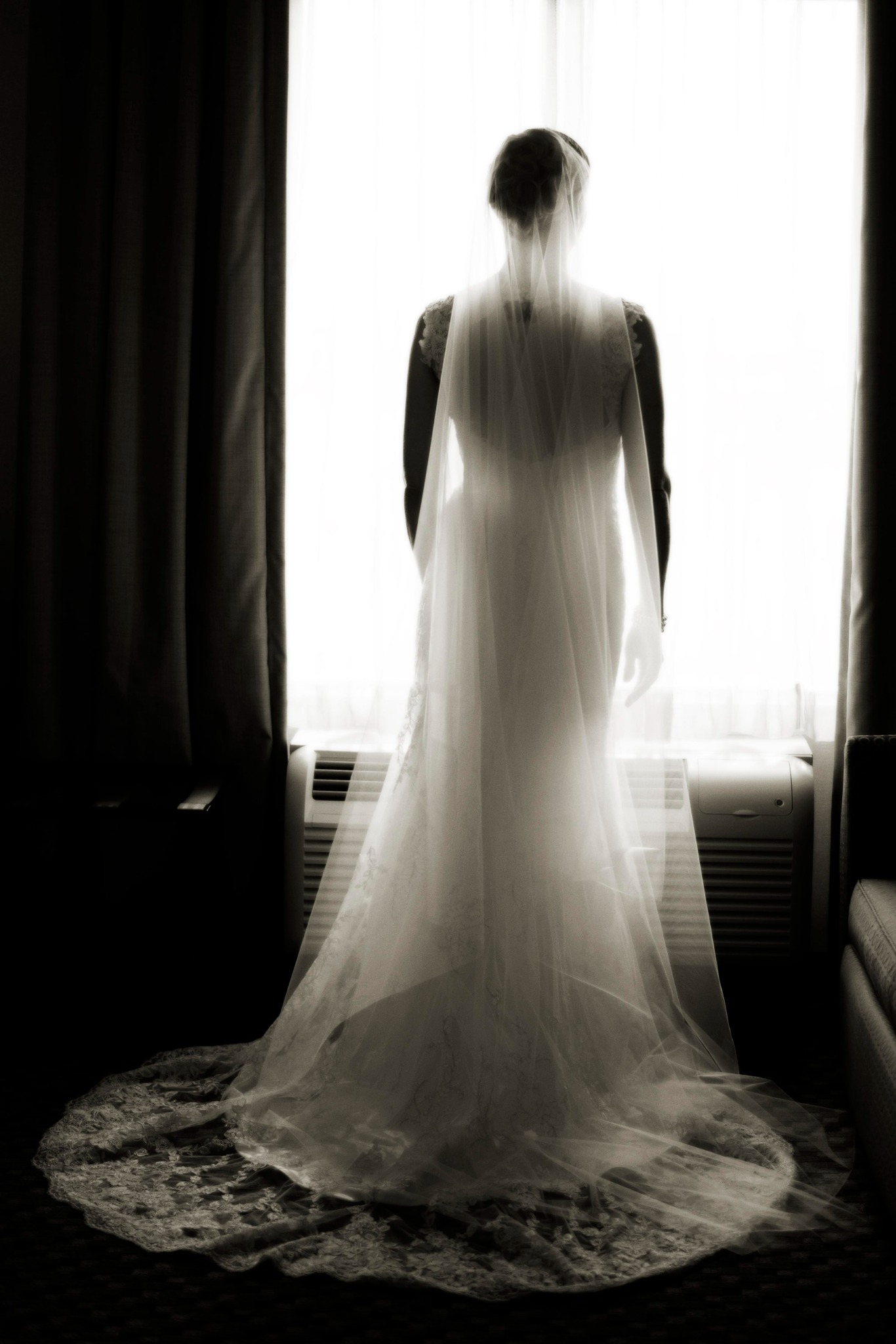 Bride silhouetted at a window beneath her wedding veil