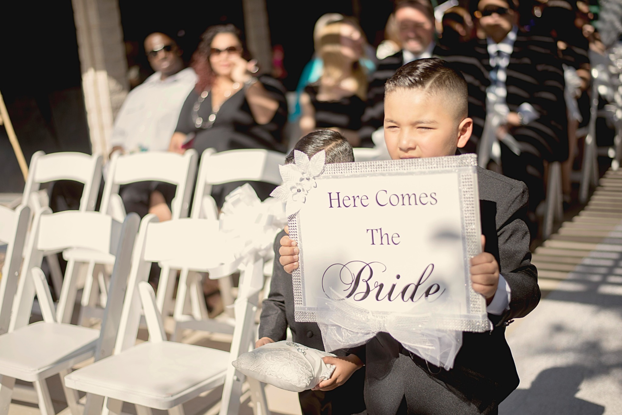 Children carrying a Here Comes the Bride sign at a wedding ceremony